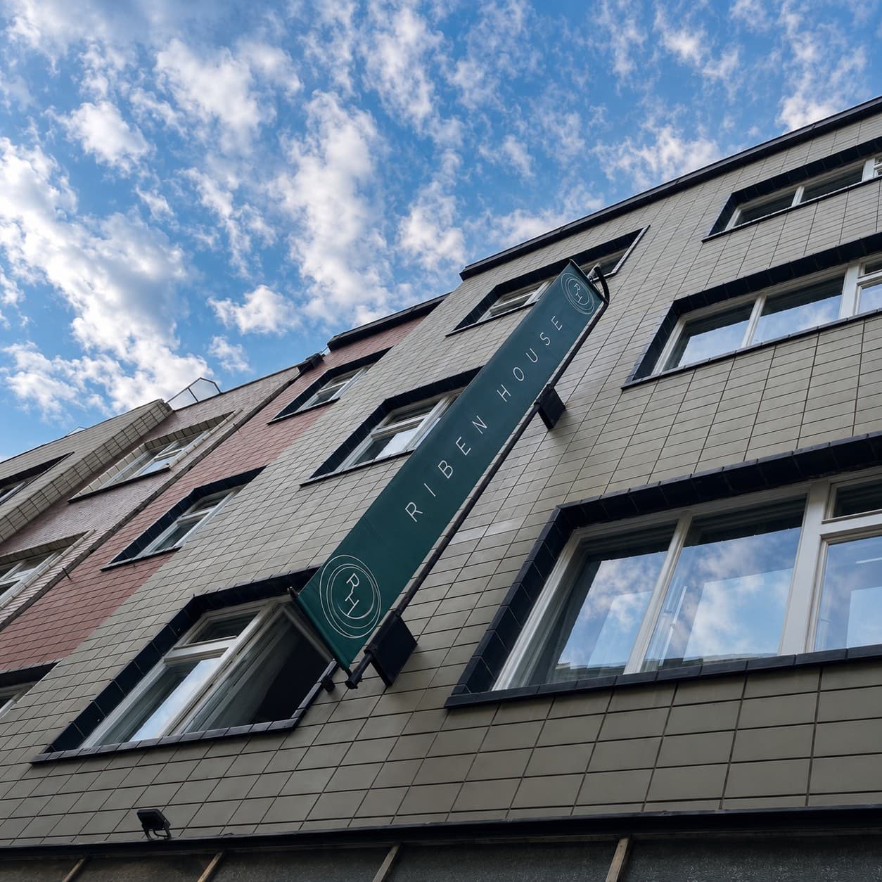 Zelený výložní banner RIBEN HOUSE na fasádě domu v centru Prahy